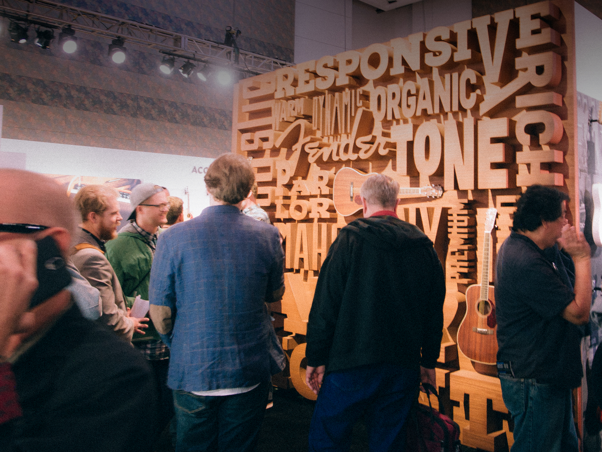 Fender custom trade show booth at NAMM: a wall of dimensional wooden lettering with visitors in front